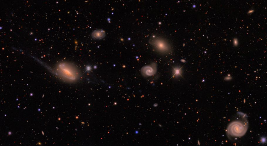 DECam image of a field in the southern constellation Lepus showing Milky Way stars (small colored dots) and a galaxy group (the larger, diffuse objects) located about 300 million light-years away. The image is a small fraction of one of the observations made with the Dark Energy Camera. The DES analysis measures the fainter galaxies visible in this image. Credits: Erin Sheldon and DES collaboration.